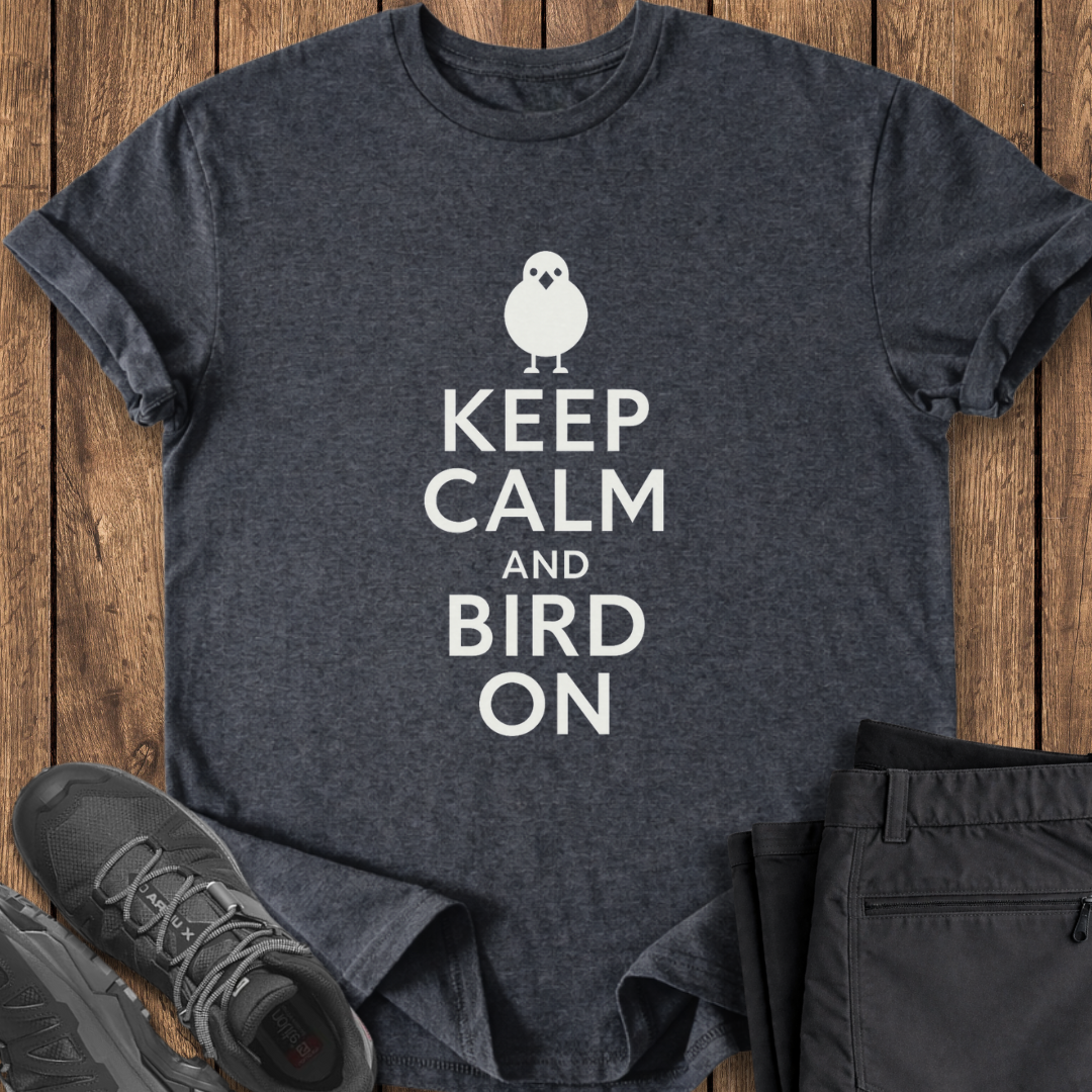 Dark gray t-shirt with 'Keep Calm and Bird On' text and graphic on a wooden surface, with shoes and pants for scale.
