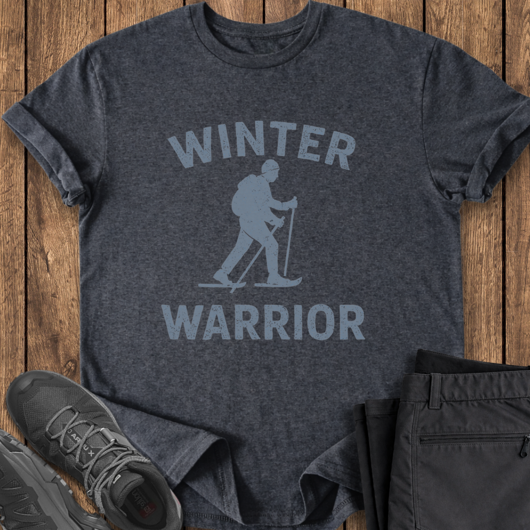 Dark gray t-shirt with 'Winter Warrior' graphic on a wooden surface, accompanied by black pants and shoes.