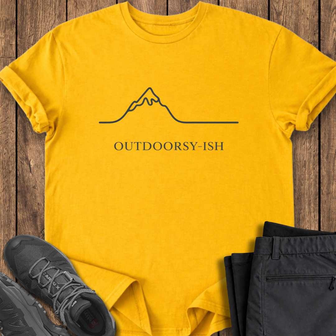 Yellow t-shirt with 'OUTDOORSY-ISH' text and mountain graphic on a wooden surface with black pants and shoes. funny outdoor t shirt