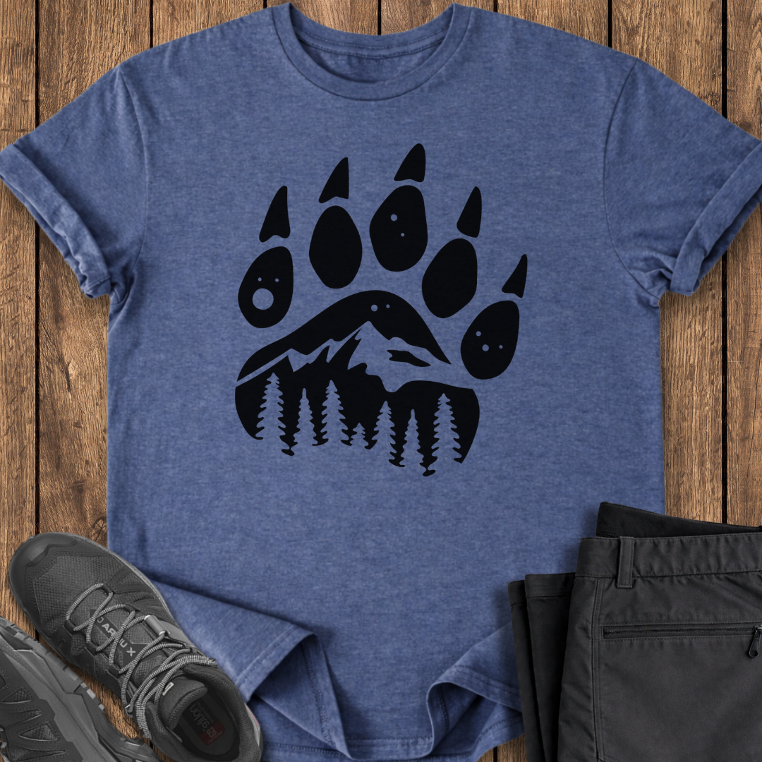 Blue t-shirt with black bear paw print design on a wooden surface with shoes and pants. bear mountain shirt