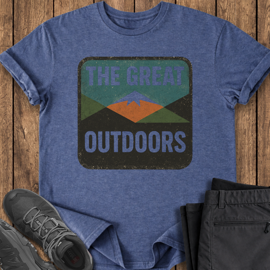 Blue t-shirt with 'The Great Outdoors' graphic on a wooden surface, with shoes and shorts in the foreground. outdoor mountain t shirt