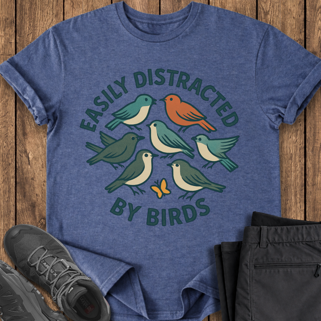 Blue t-shirt with bird design and text on a wooden surface with shoes and pants. bird lover t shirt