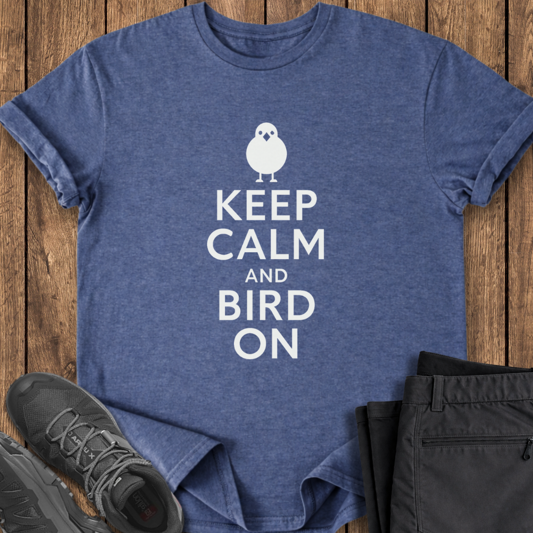 Blue t-shirt with 'Keep Calm and Bird On' text on a wooden surface with shoes and shorts.