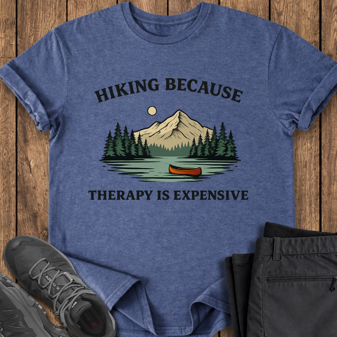Blue t-shirt with hiking graphic and text on a wooden surface with shoes and shorts. mental health outdoor shirt