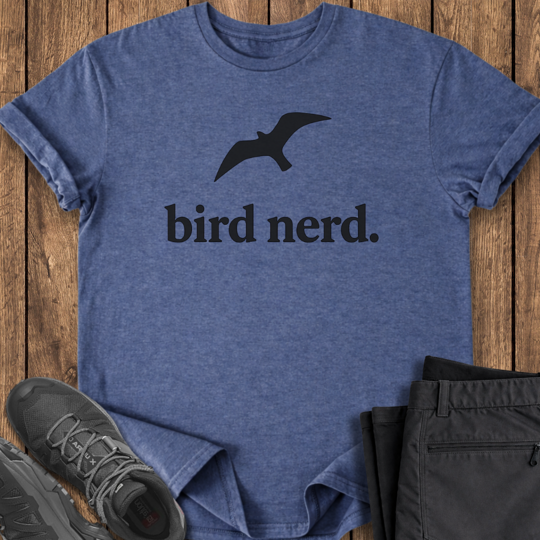 Blue t-shirt with 'bird nerd' text and a bird graphic on a wooden surface, with shoes and pants partially visible.