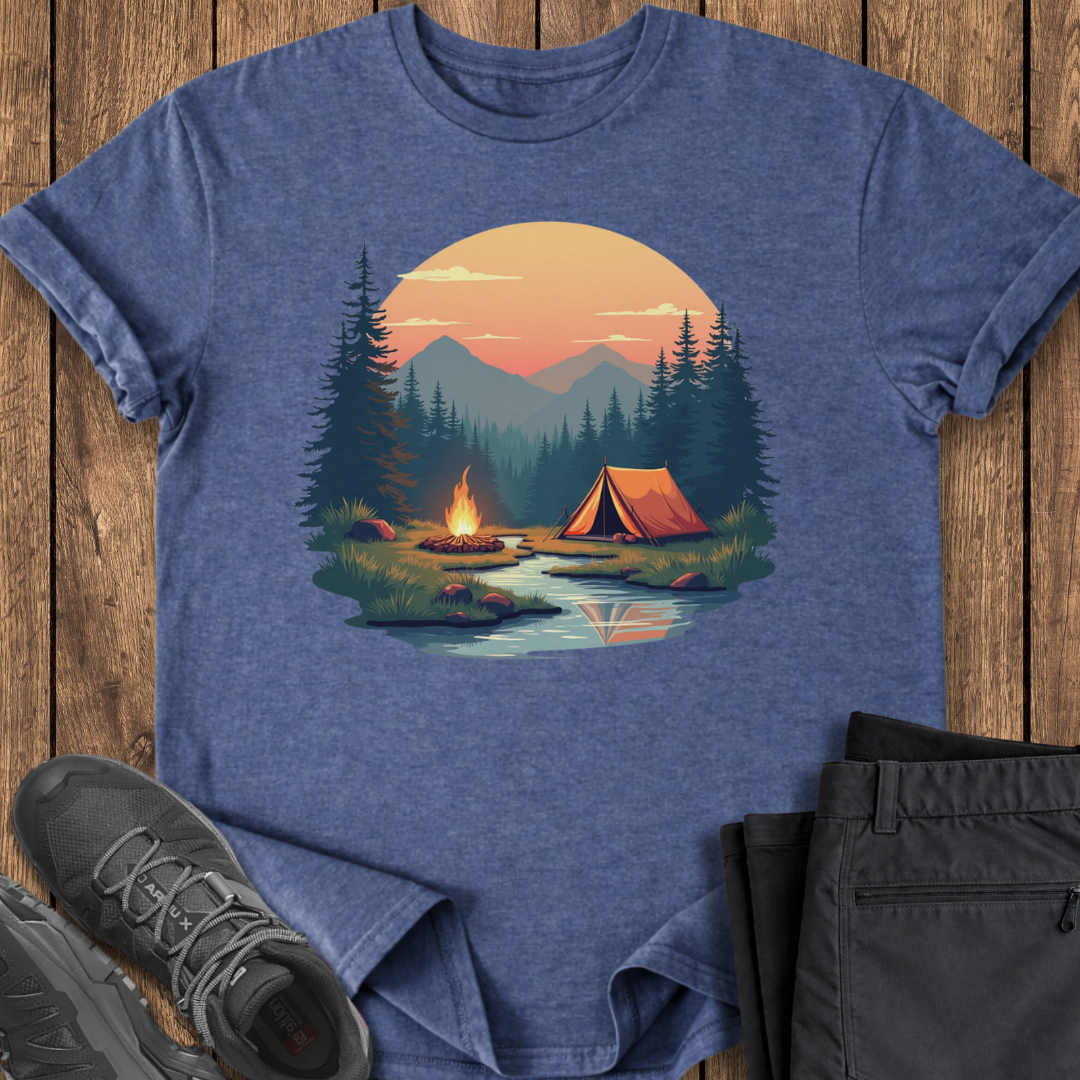 Blue t-shirt with a camping graphic on a wooden surface with shoes and pants.