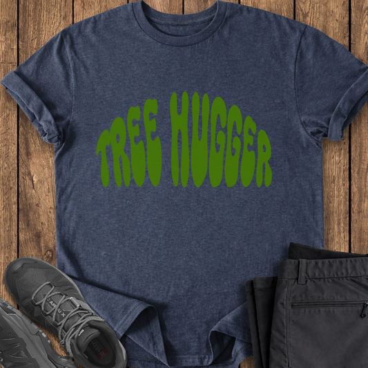 Blue t-shirt with 'TREE HUGGER' text on a wooden surface, with shoes and pants partially visible.