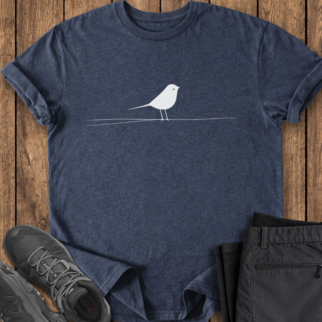 Navy blue t-shirt with a white bird design on a wooden surface, accompanied by black shoes and pants.