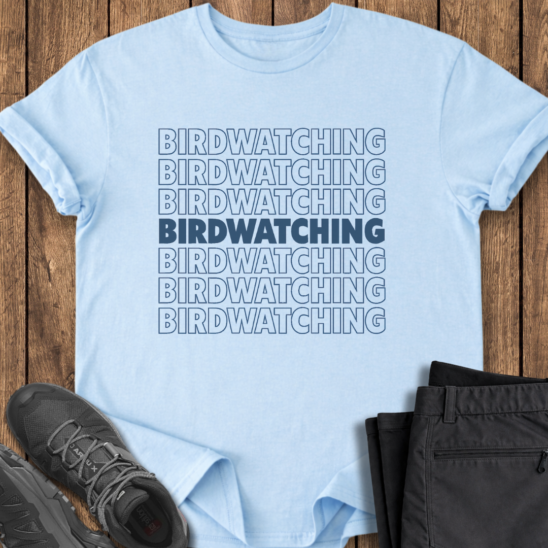Light blue t-shirt with 'BIRDWATCHING' text on a wooden surface with shoes and pants.