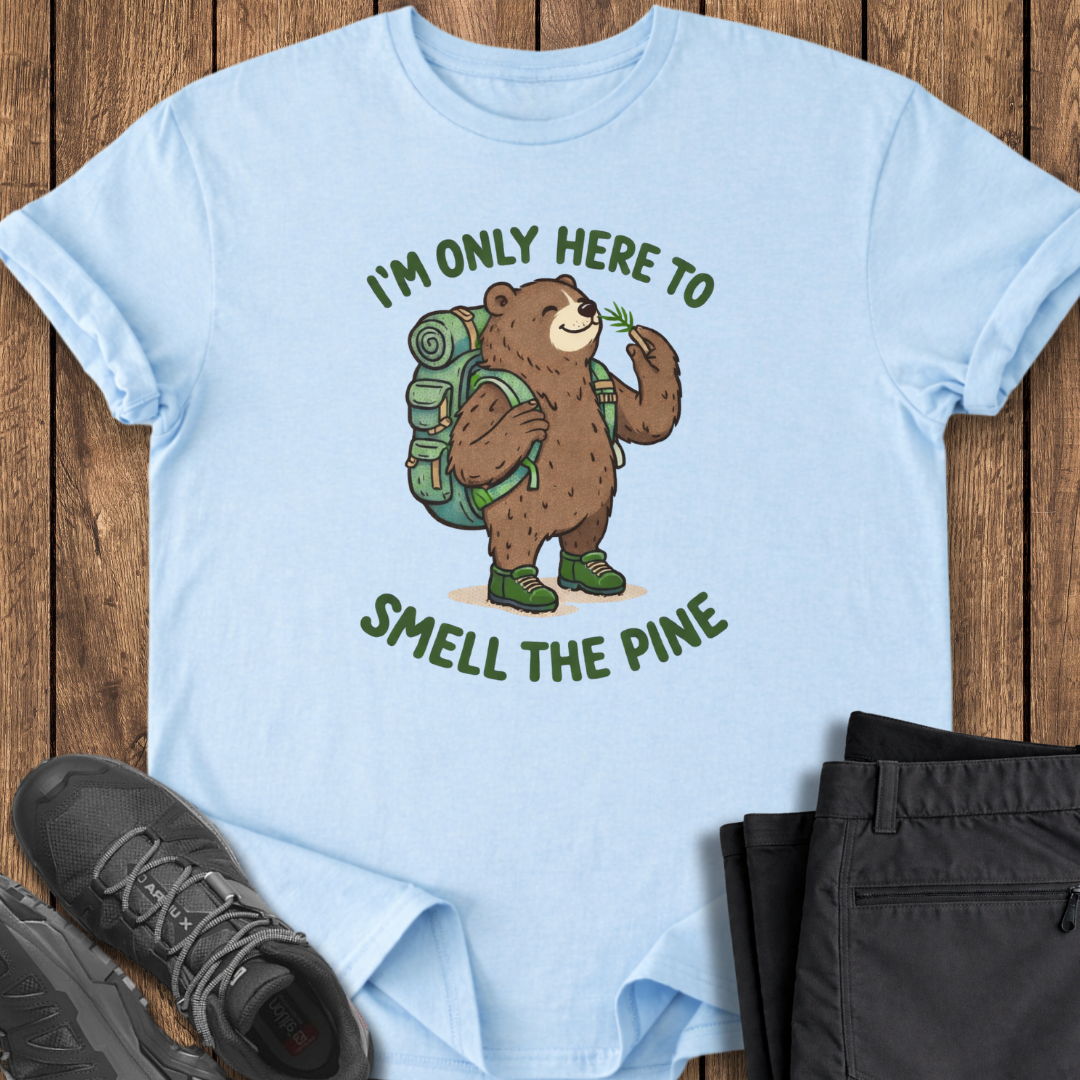 Light blue t-shirt with bear graphic and text on a wooden surface with shoes and pants. funny bear hiking t shirt