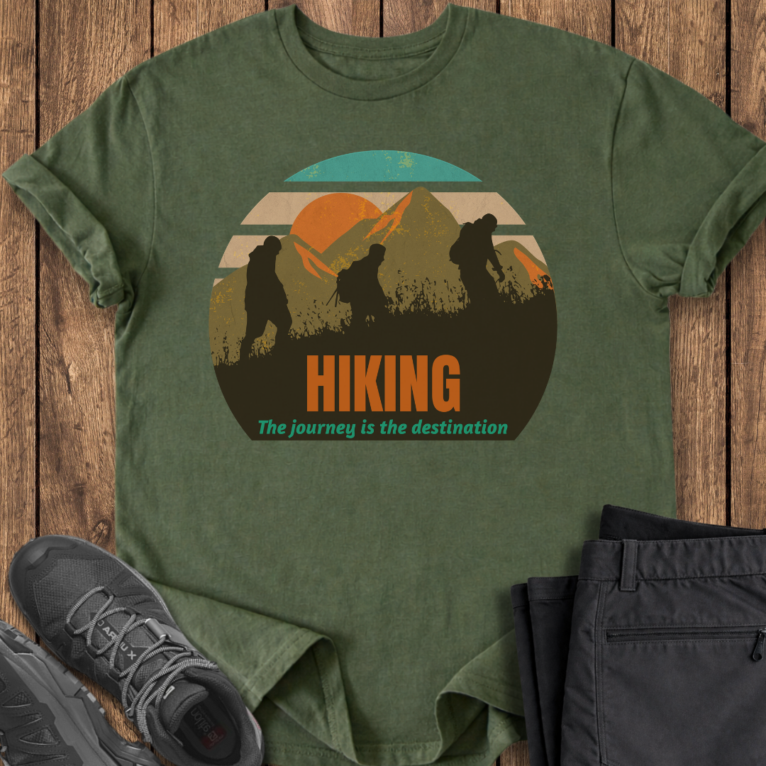 Green t-shirt with hiking graphic and text on a wooden surface, accompanied by hiking shoes and pants. three hikers backpackers backpacking mindful mindfulness t shirt