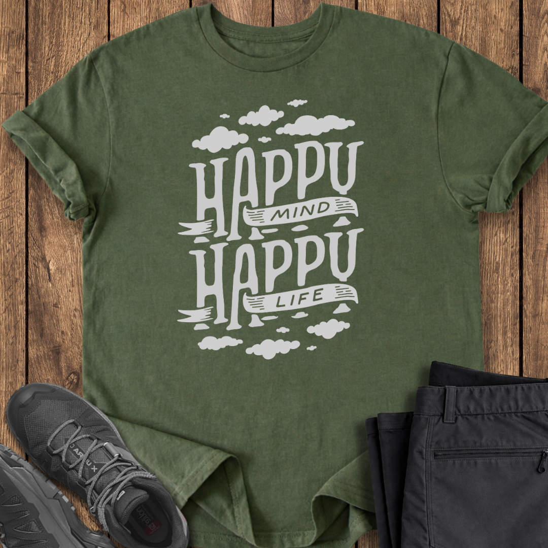 Green t-shirt with 'Happy Mind Happy Life' text on a wooden surface with shoes and pants.
