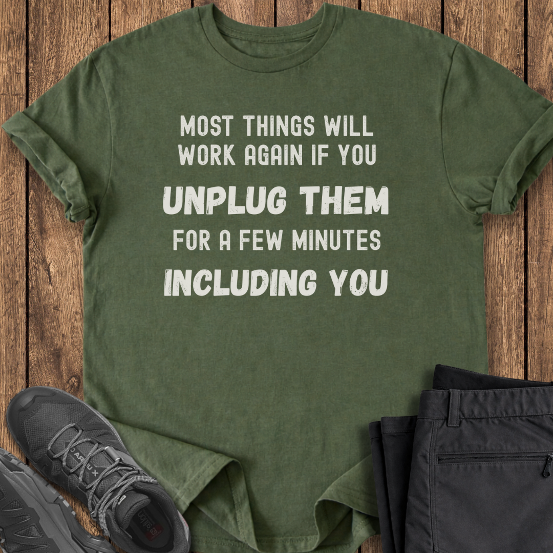Green t-shirt with humorous text on a wooden surface with shoes and pants.