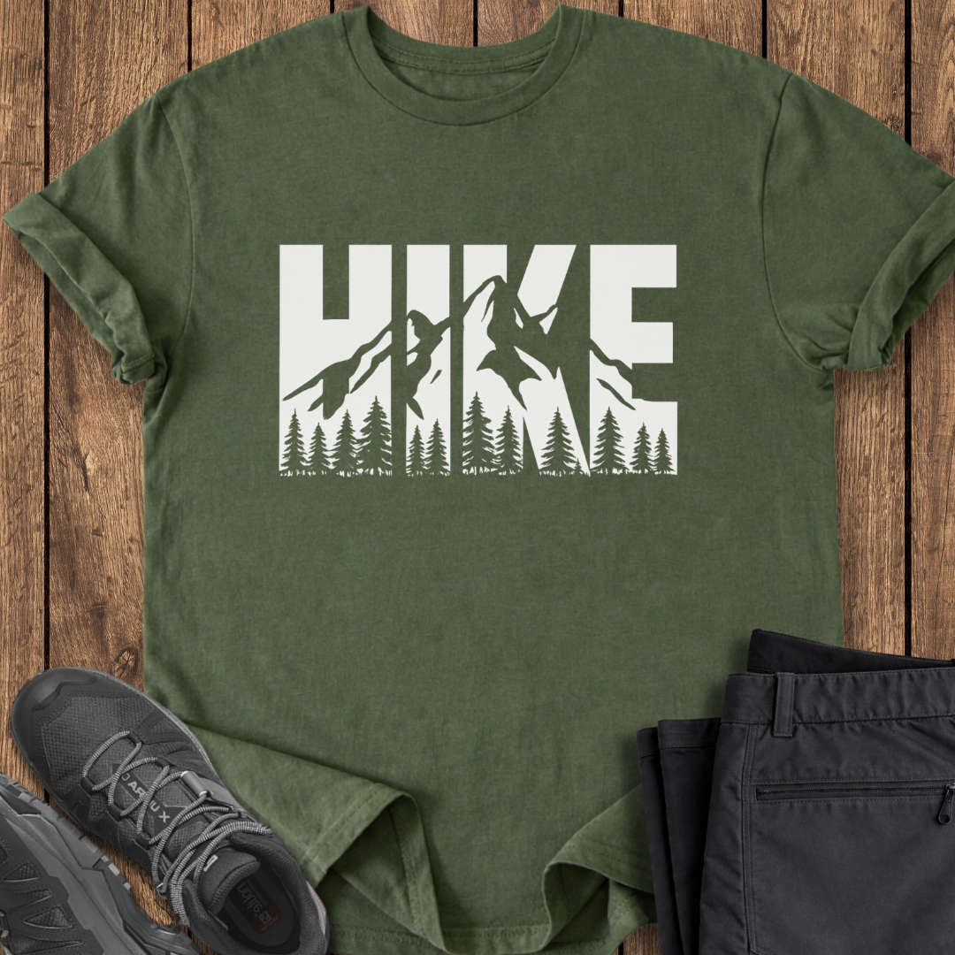 Green t-shirt with 'HIKE' graphic on a wooden surface with shoes and pants.