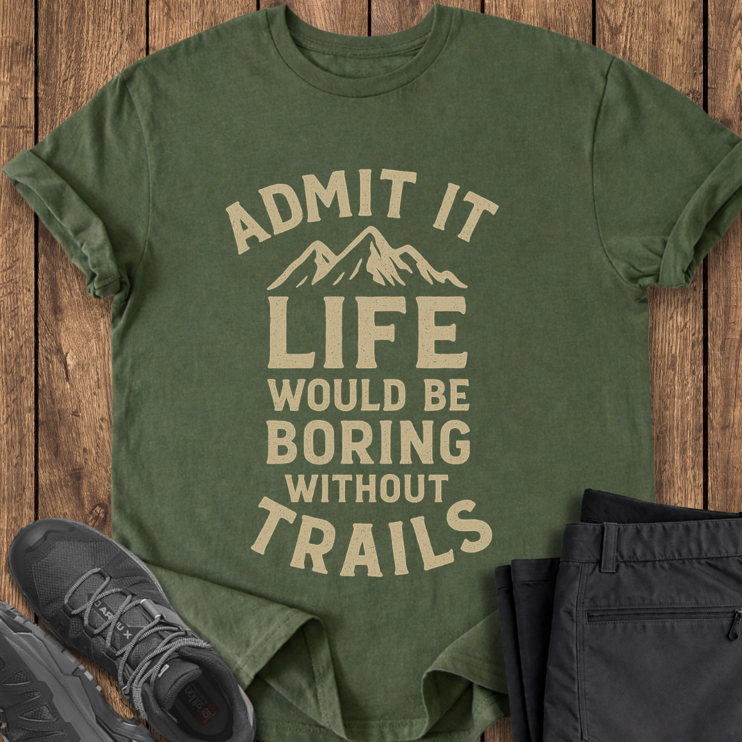 Green t-shirt with 'Admit it, life would be boring without trails' text on a wooden surface with shoes and pants. hiking t shirt