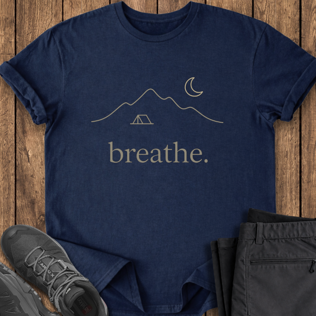 Navy blue t-shirt with 'breathe.' design on a wooden surface with shoes and pants.
