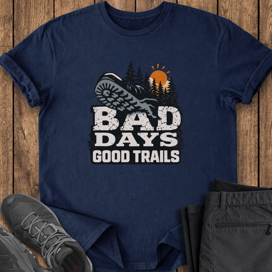 Navy blue t-shirt with 'Bad Days Good Trails' graphic on a wooden surface with shoes and pants. mental health hiking t shirt