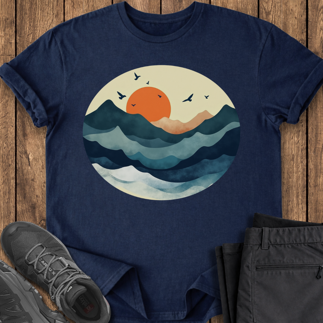 Navy blue t-shirt with a sunset and wave design on a wooden surface with shoes and pants.