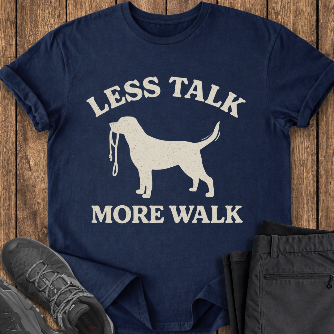 Navy blue t-shirt with white dog graphic and text 'LESS TALK MORE WALK' on a wooden surface.