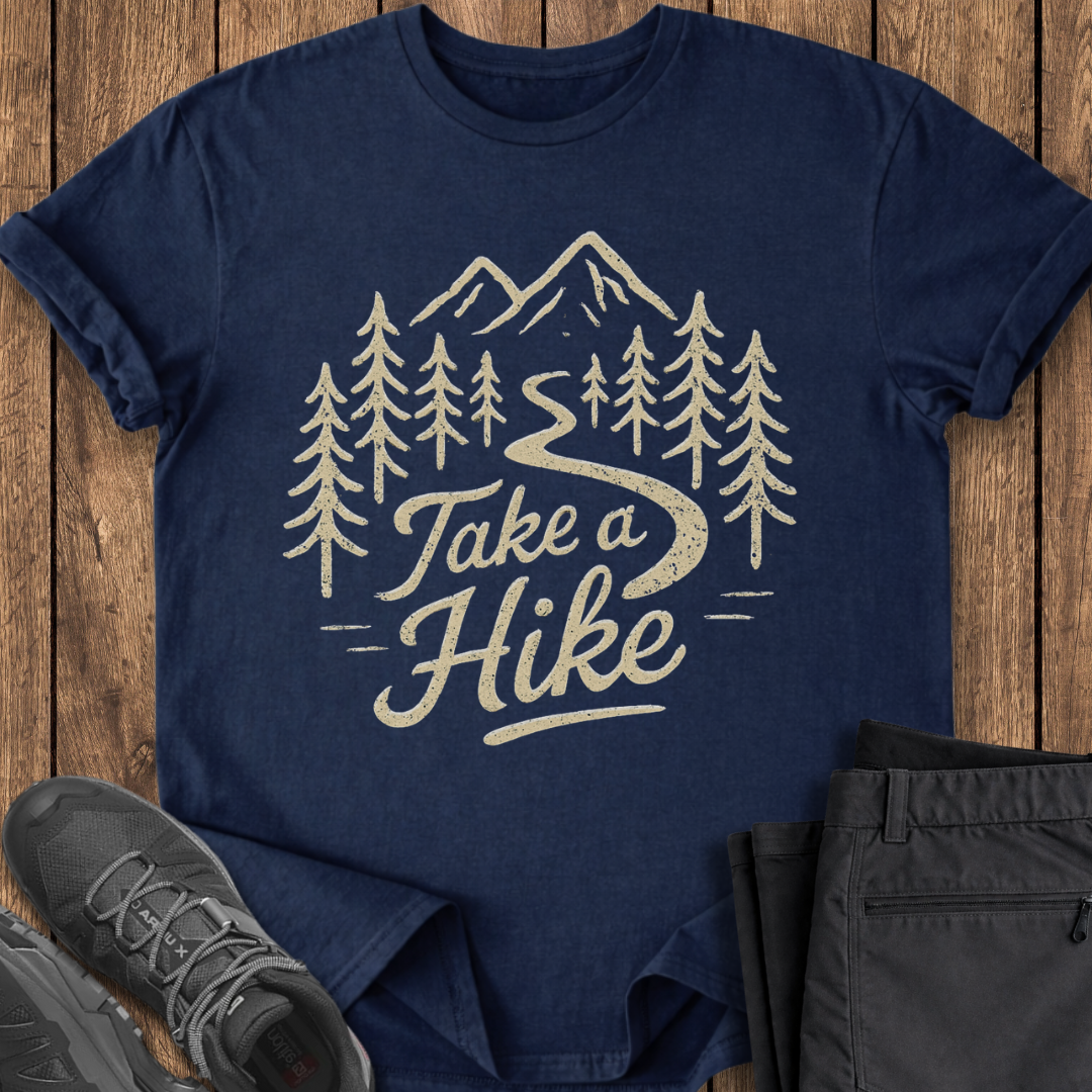 Navy blue t-shirt with 'Take a Hike' graphic on a wooden surface with shoes and pants.