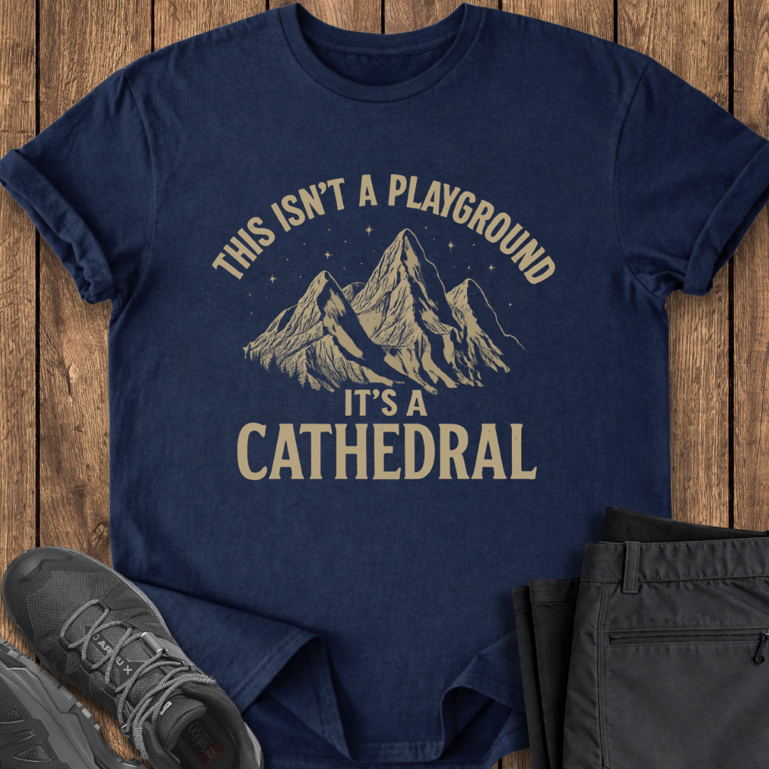Navy blue t-shirt with mountain graphic and text on a wooden surface with shoes and pants.