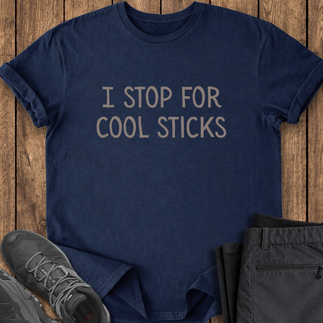 Navy blue t-shirt with 'I STOP FOR COOL STICKS' text on a wooden surface with shoes and pants. funny hiking t shirt