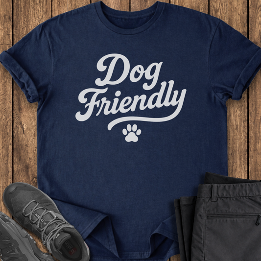 Navy blue t-shirt with 'Dog Friendly' text on a wooden surface with shoes and pants.