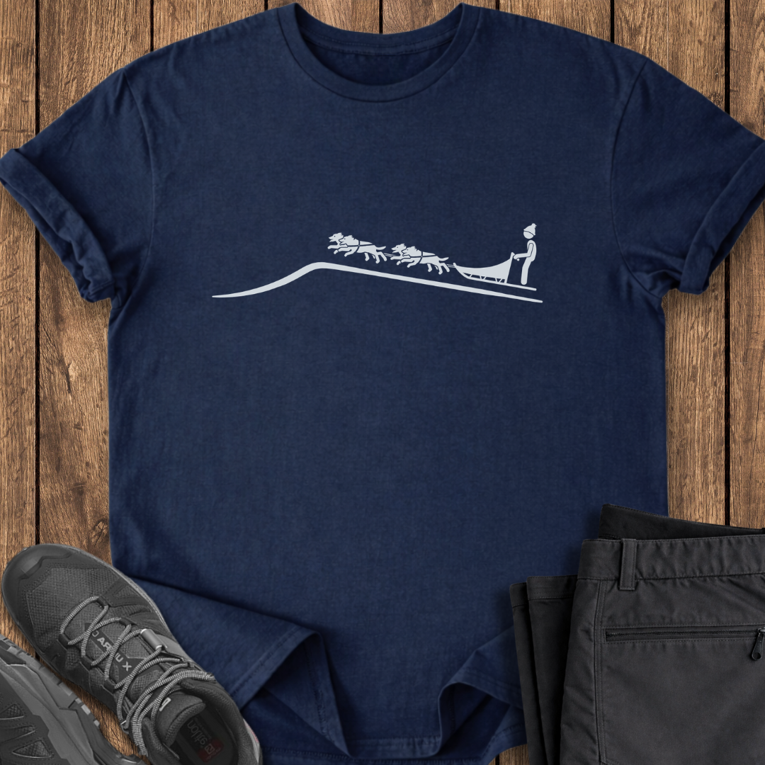 Navy blue t-shirt with white graphic design on a wooden surface, accompanied by gray sneakers and black pants. dogsledding tee