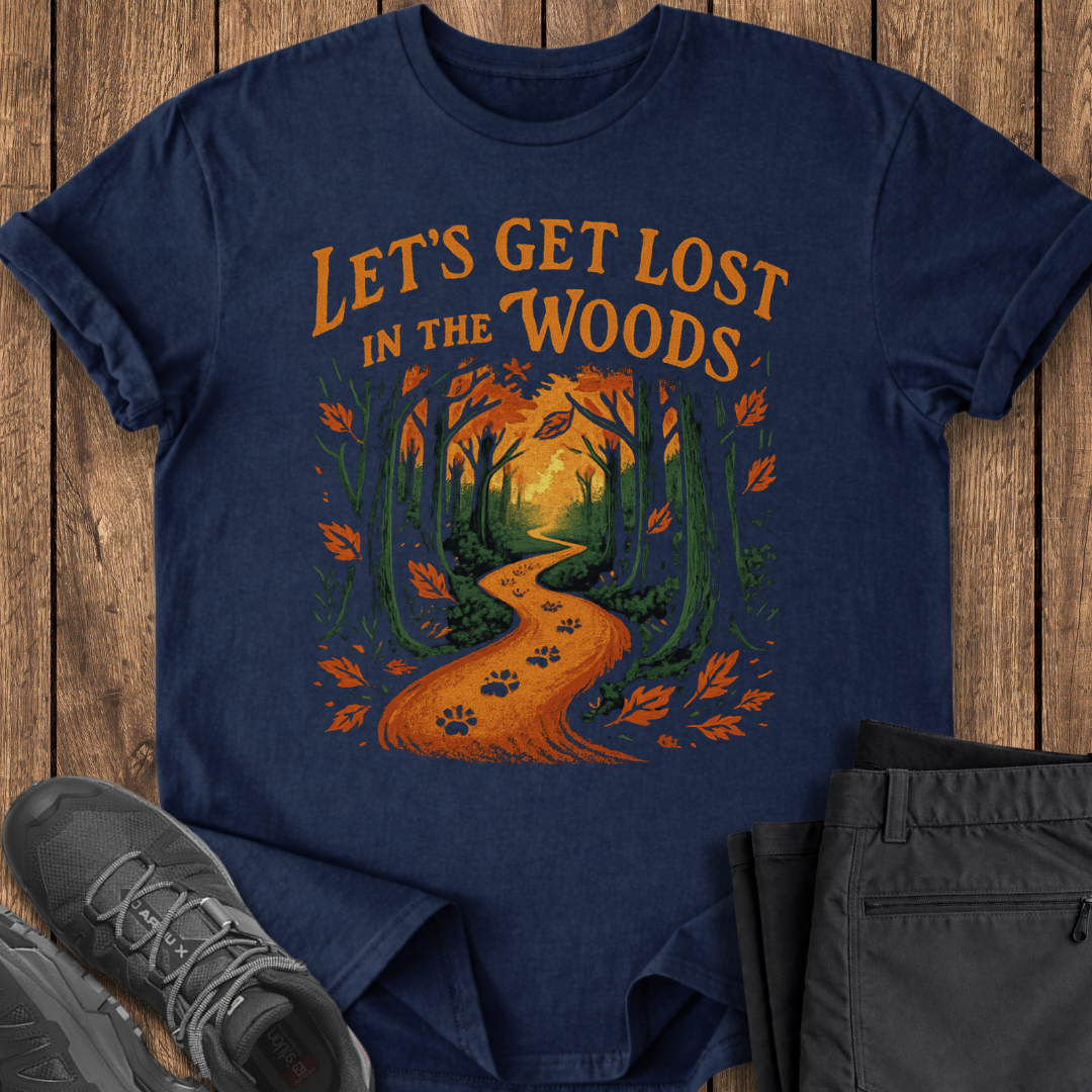 Navy blue t-shirt with 'Let's Get Lost in the Woods' design on a wooden surface with shoes and pants.