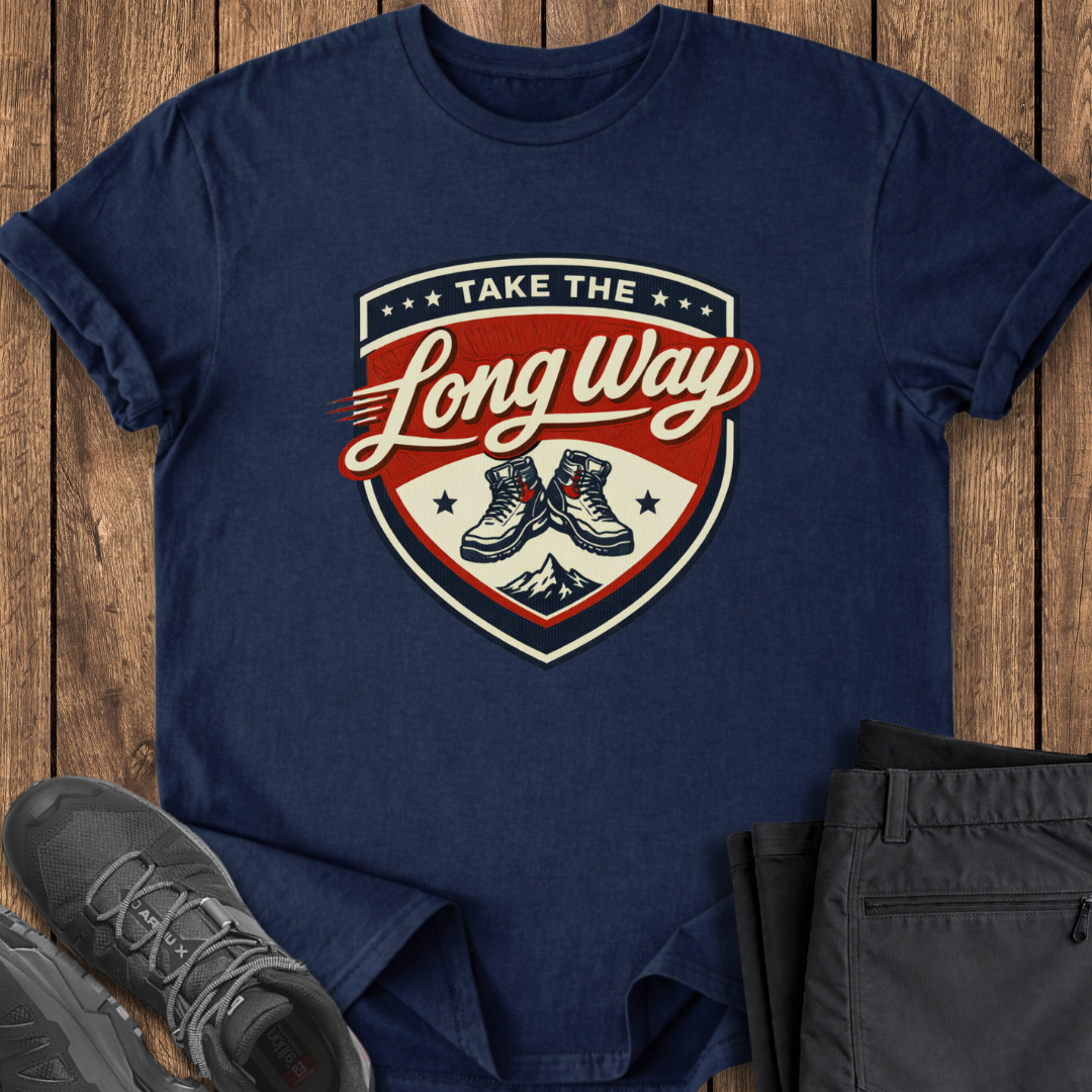Navy blue t-shirt with 'Take the Long Way' graphic on a wooden surface with shoes and pants.