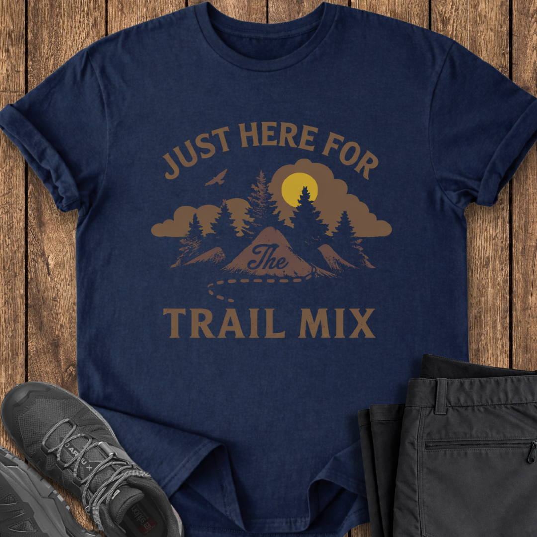 Navy blue t-shirt with mountain graphic and text 'Just Here for the Trail Mix' on a wooden surface with shoes and shorts. funny hiking tralmix tshirt