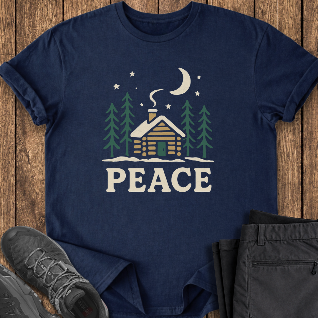 Navy blue t-shirt with a cabin and 'PEACE' design on a wooden surface with shoes and pants.
