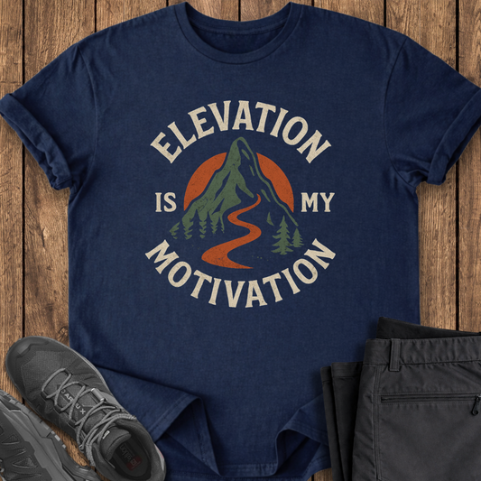 Navy blue t-shirt with 'Elevation is My Motivation' graphic on a wooden surface with shoes and pants. hiking mountaineering climbing t shirt