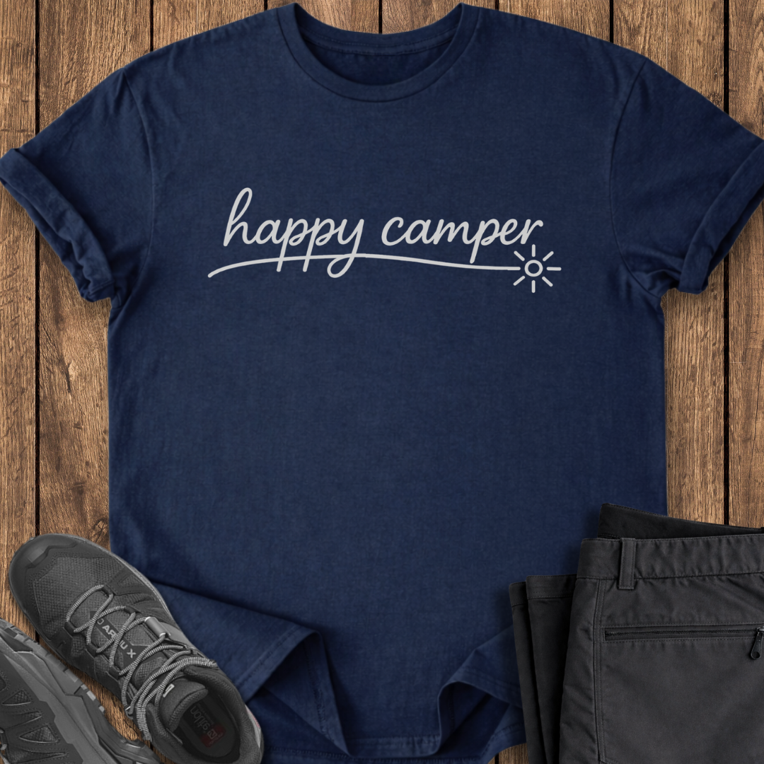 Navy blue t-shirt with 'happy camper' text on a wooden surface with shoes and pants.
