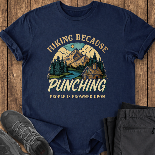 Navy blue t-shirt with hiking graphic and text on a wooden surface with shoes and pants. funny hiking tshirt punching is frowned upon