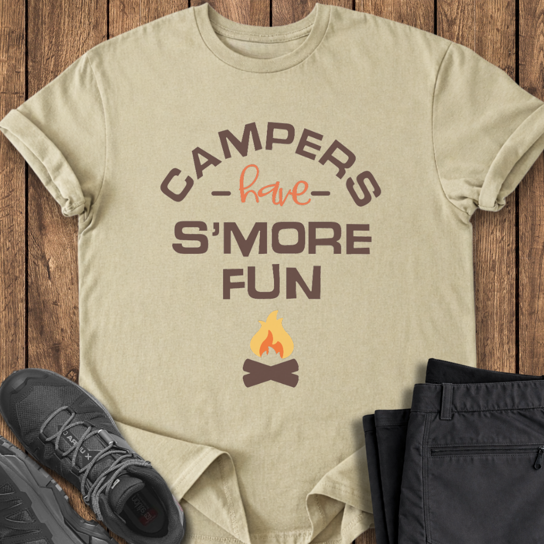 Beige t-shirt with 'Campers have S'more Fun' text and campfire graphic on a wooden surface with shoes and pants. funny campfire t shirt