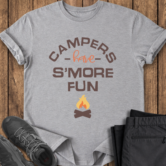 Gray t-shirt with 'Campers have S'more Fun' text and campfire graphic on a wooden surface with shoes and pants. campfire funny t shirt