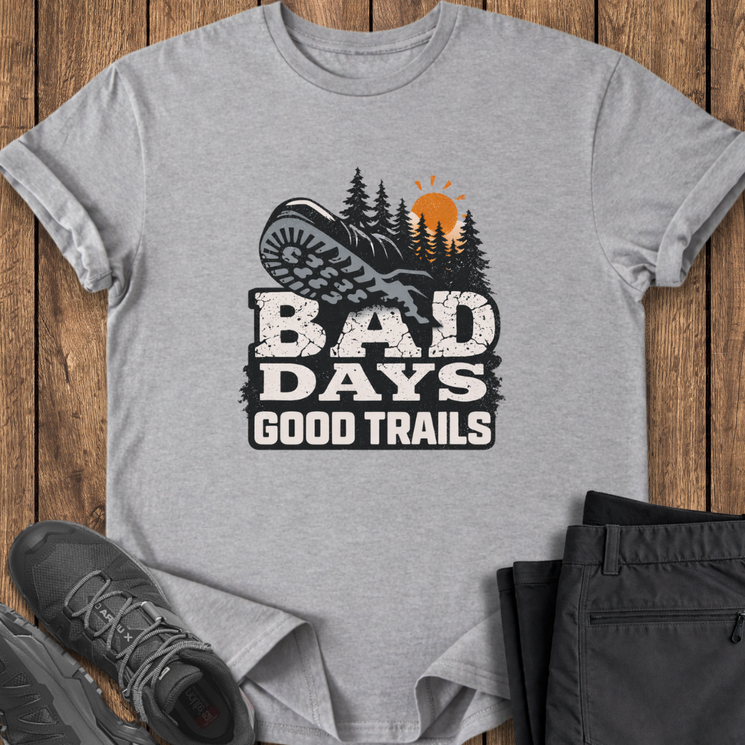 Gray t-shirt with 'Bad Days Good Trails' graphic on a wooden surface with shoes and pants. mental health outdoor shirt
