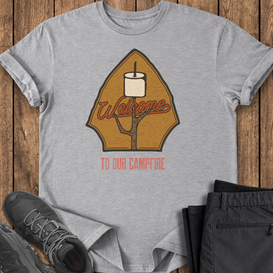 Gray t-shirt with a graphic design on a wooden surface with shoes and pants. welcome to the campfire, marshmellow shirt