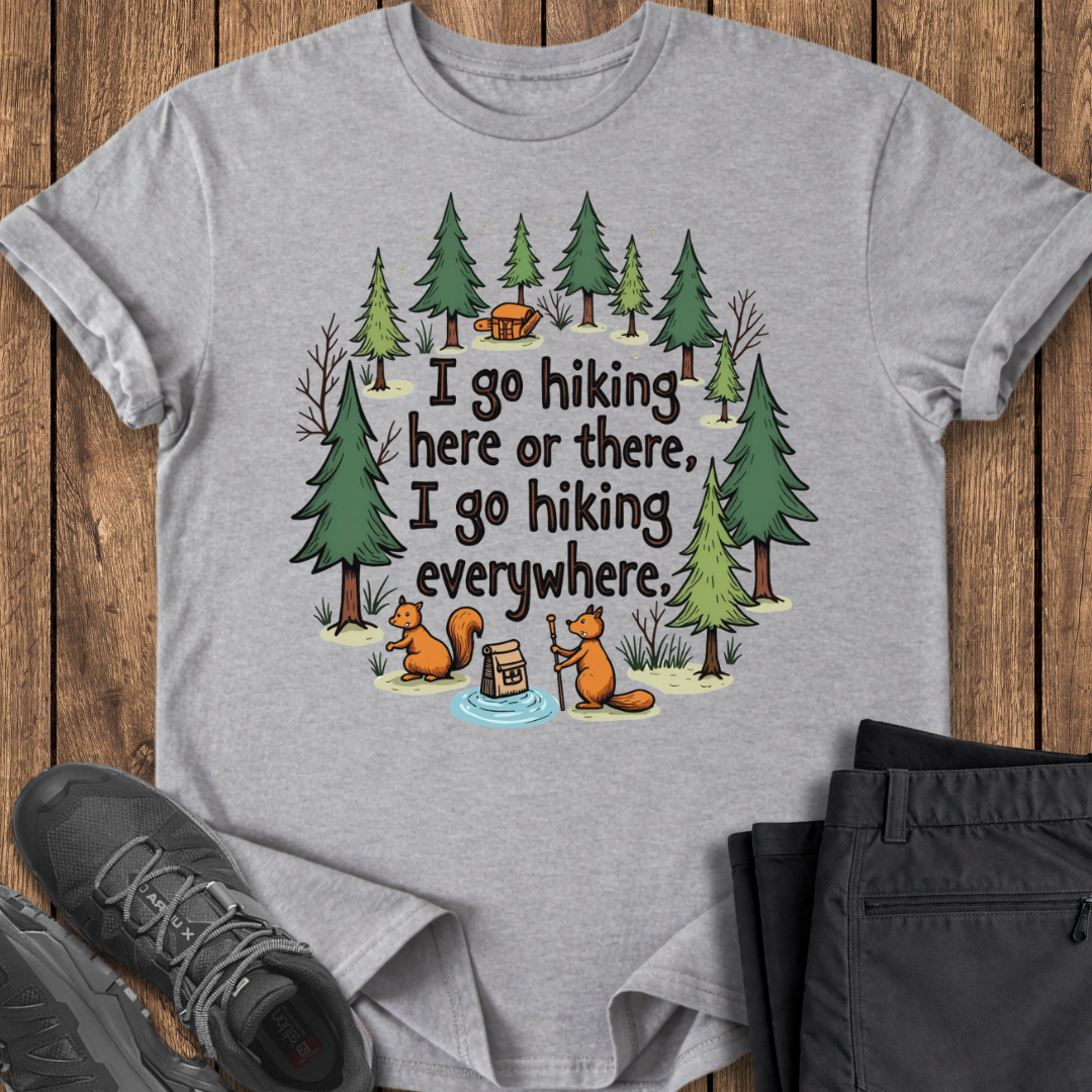 Gray t-shirt with hiking-themed design featuring trees, a cabin, and animals on a wooden surface.