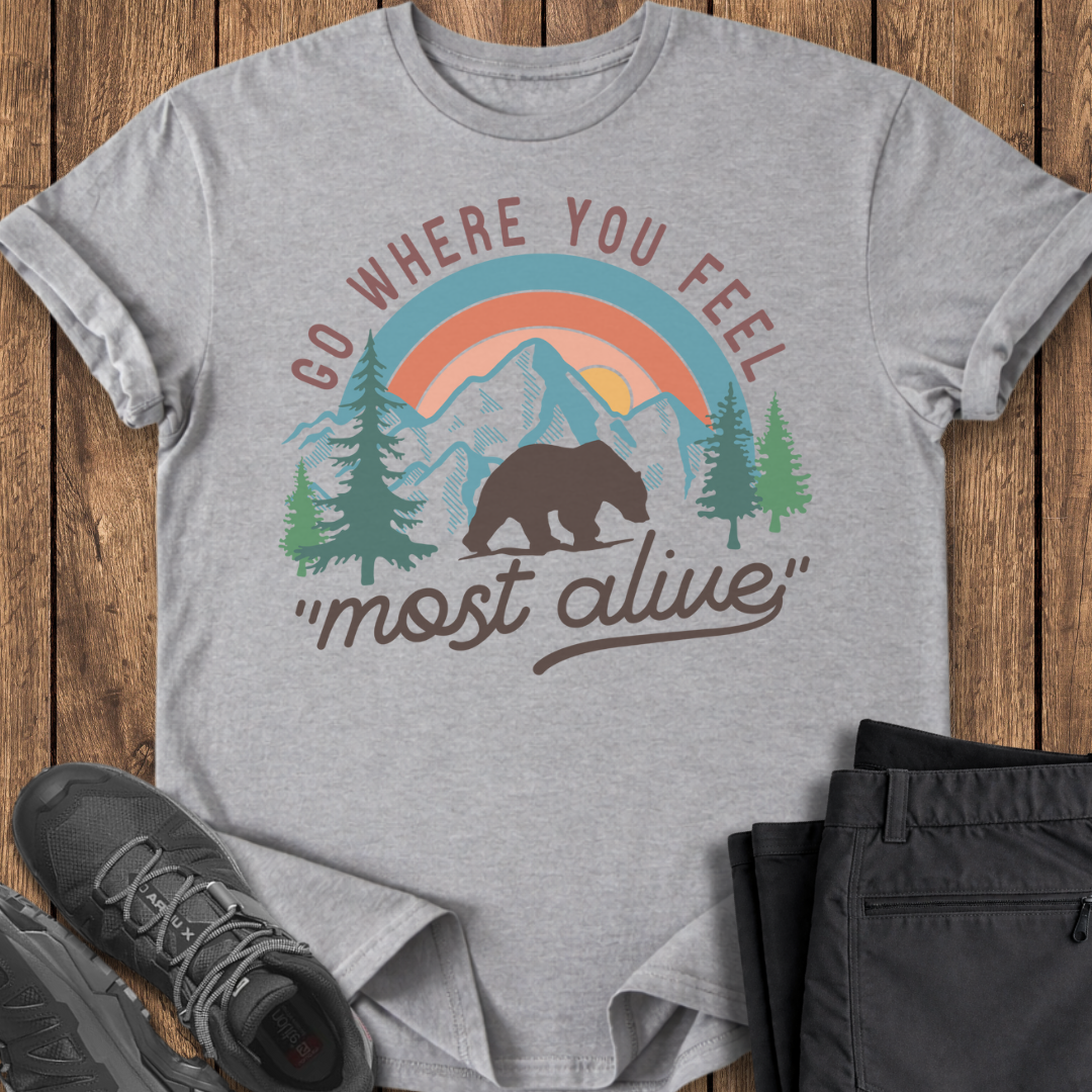 Gray t-shirt with nature-themed graphic and text on a wooden surface with shoes and pants.