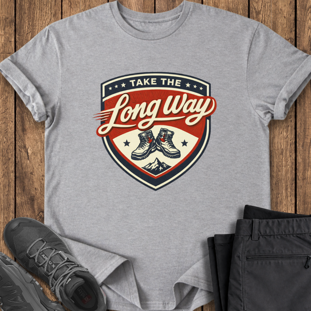 Gray t-shirt with 'Take the Long Way' graphic on a wooden surface with shoes and pants.