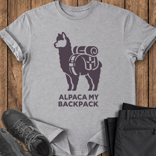 Gray t-shirt with alpaca graphic and 'Alpaca My Backpack' text on a wooden surface, with shoes and pants for scale. funny backpack hike t shirt