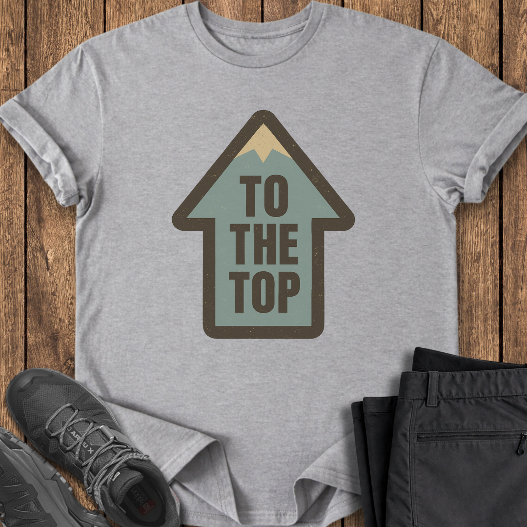Gray t-shirt with 'To The Top' graphic on a wooden surface with shoes and pants.