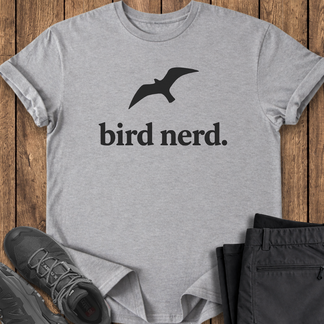 Gray t-shirt with 'bird nerd' text and bird graphic on a wooden surface with shoes and pants.