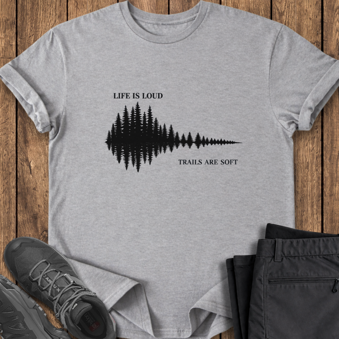 Gray t-shirt with nature-themed design on a wooden surface with shoes and pants. mindful hiking t shirt