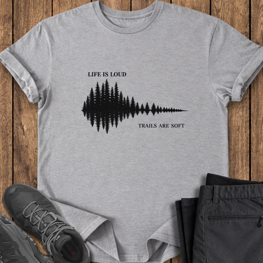 Gray t-shirt with nature-themed design on a wooden surface with shoes and pants. mindful hiking t shirt