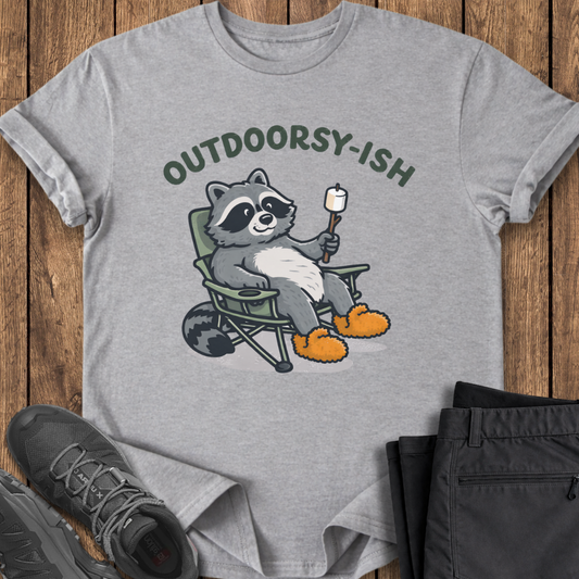 Gray t-shirt with a raccoon graphic and 'Outdoorsy-ish' text on a wooden surface, with shoes and pants for scale. hiking t shirts